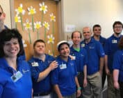 Men and women smiling in blue shirts